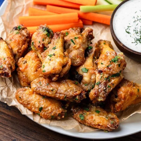 Garlic parmesan chicken wings in white plate with carrots and celery.