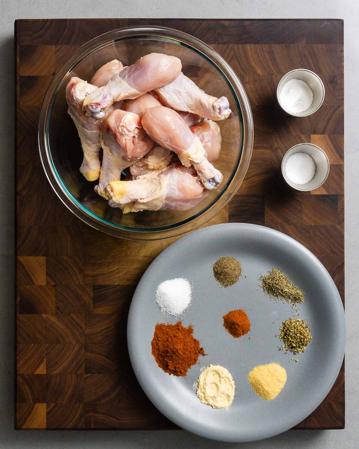 Ingredients shown: bowl of chicken legs, baking powder, salt, and spices for Cajun seasoning.
