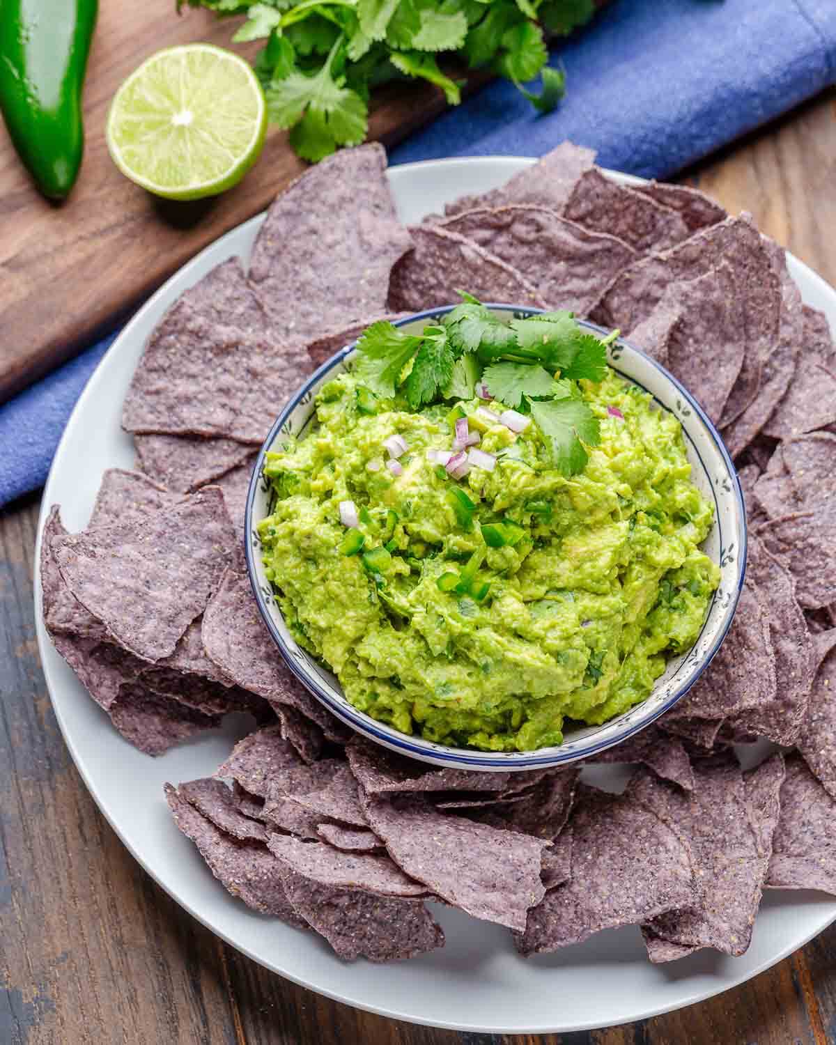 Large platter with bowl of guacamole and tortilla chips.