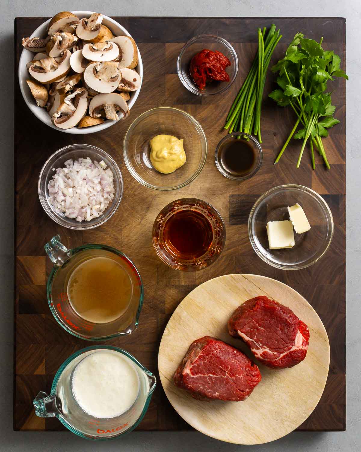 Mise en place example showing: mushrooms, tomato paste, herbs, mustard, shallot, wine, butter, stock, cream, and filet mignon.
