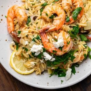Orzo with shrimp and feta in white plate.