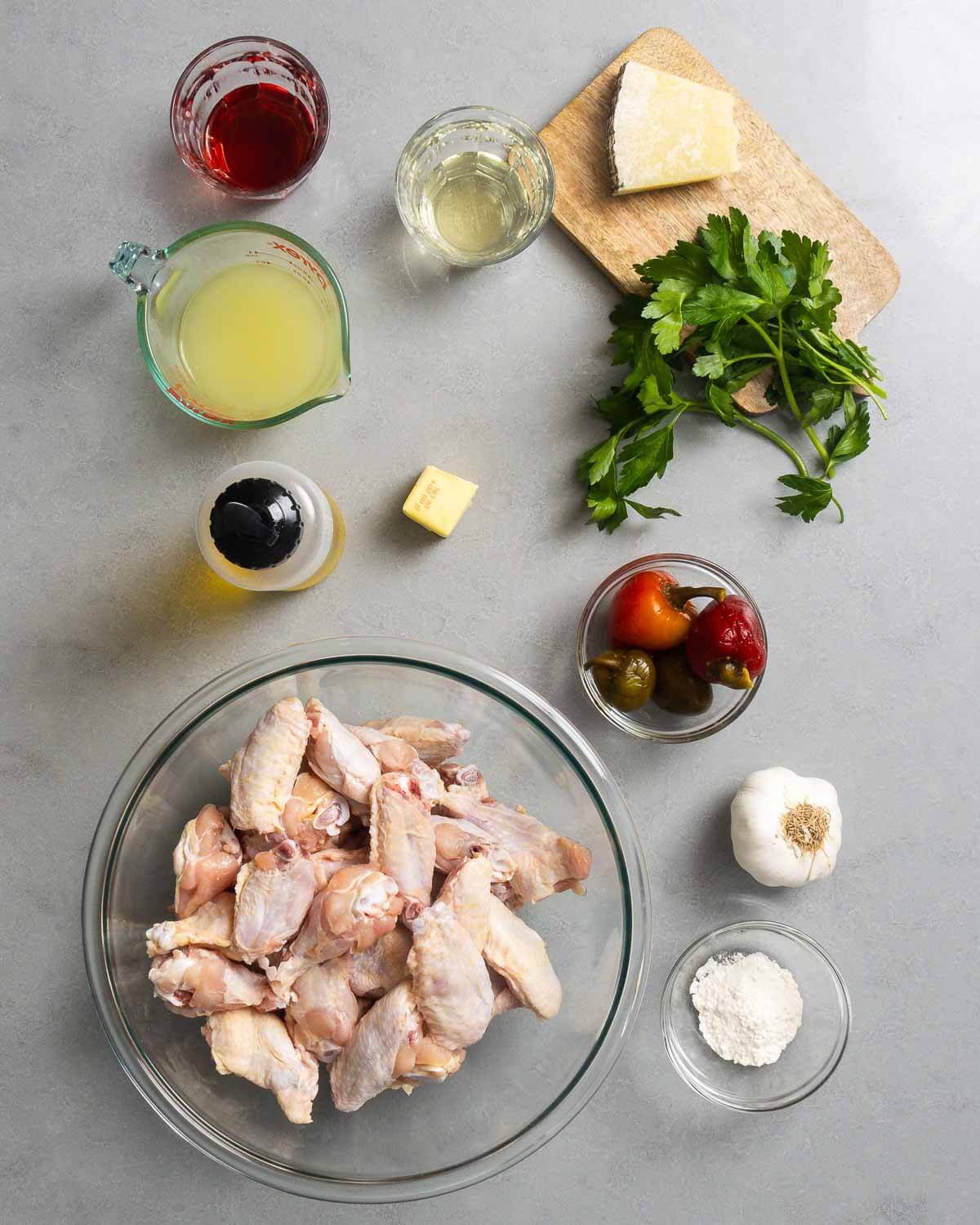 Ingredients shown: vinegar, chicken stock, wine, Pecorino Romano, parsley, butter, olive oil, chicken wings, cherry peppers, garlic, and flour.