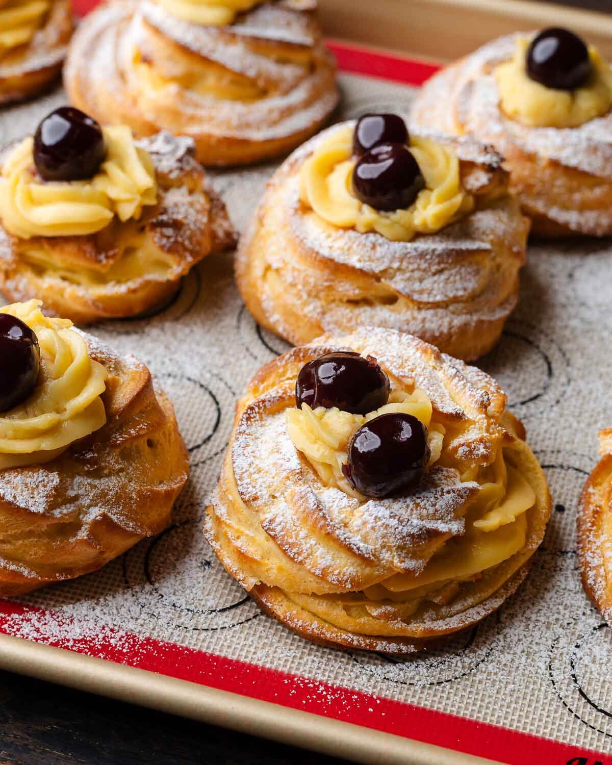 A bunch of zeppole di san Giuseppe pastries on baking sheet.