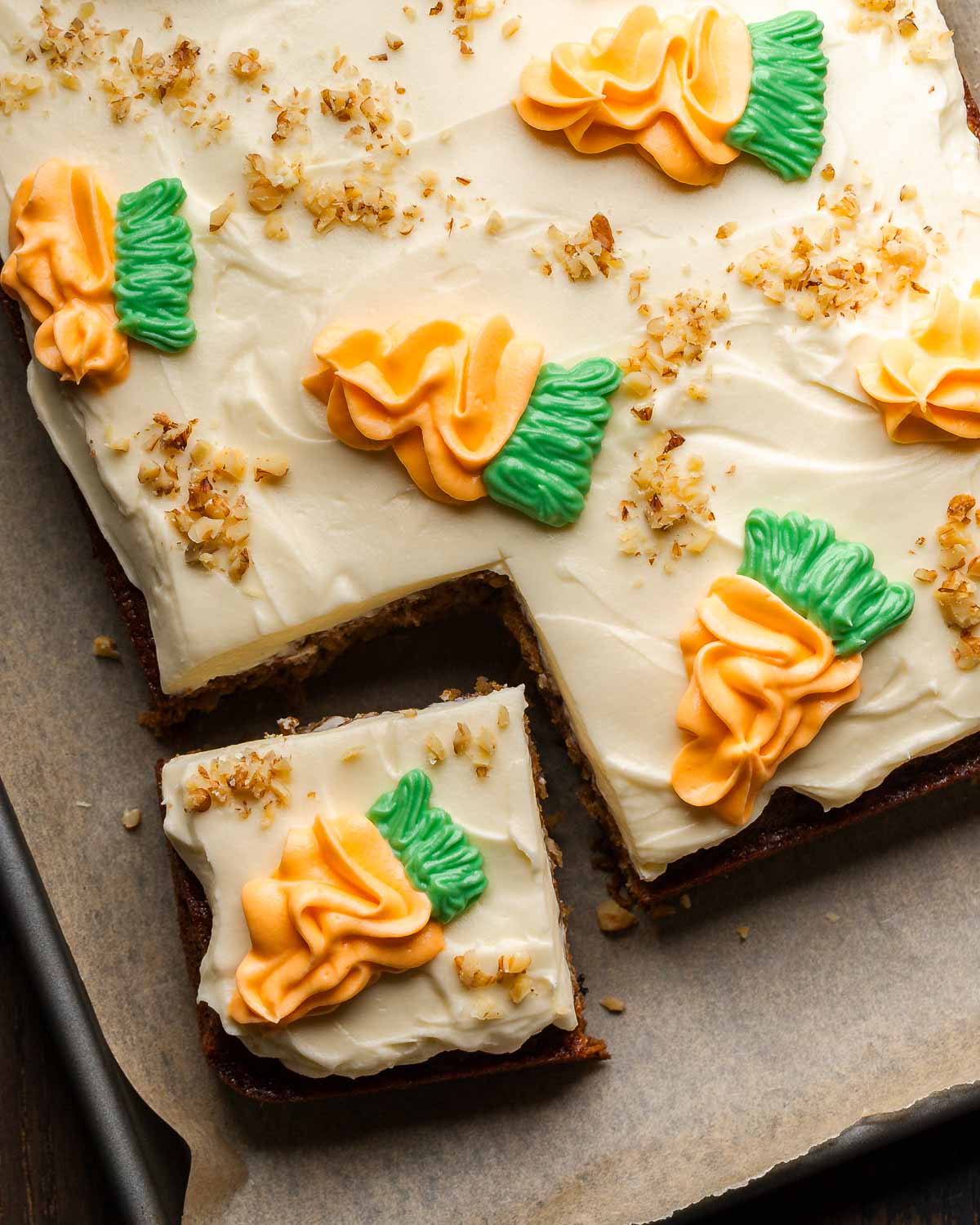 Carrot cake on baking sheet with slice cut out of it and set to the side.