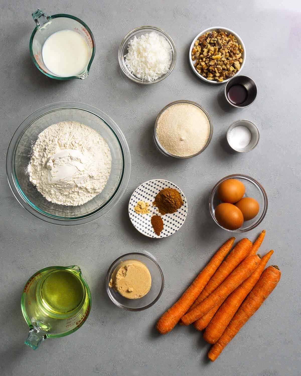 Ingredients shown: milk, coconut, walnuts, vanilla, baking soda, flour, sugar, cinnamon, nutmeg, ginger, eggs, vegetable oil, brown sugar, and carrots.