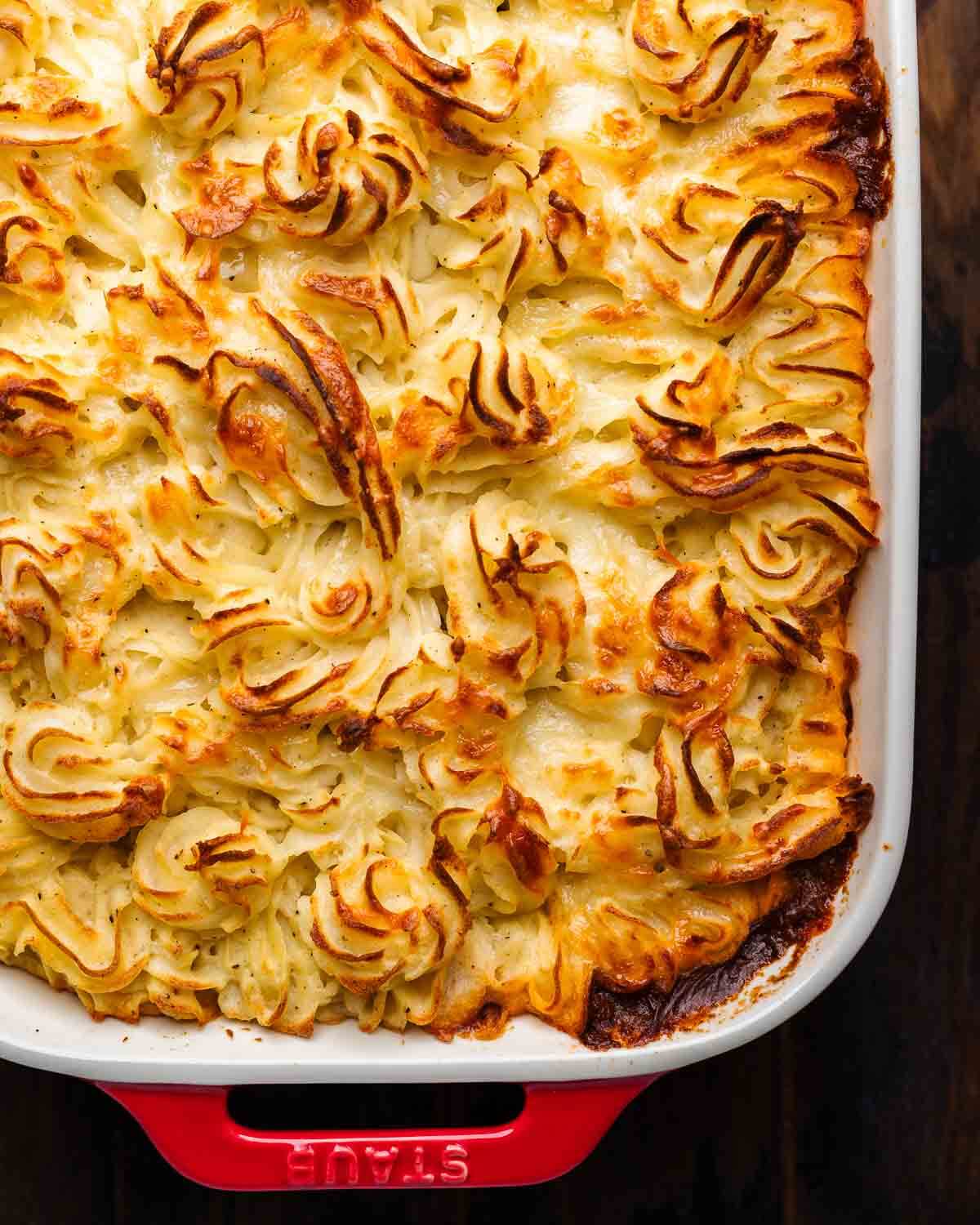 Overhead shot of cottage pie in red baking dish.