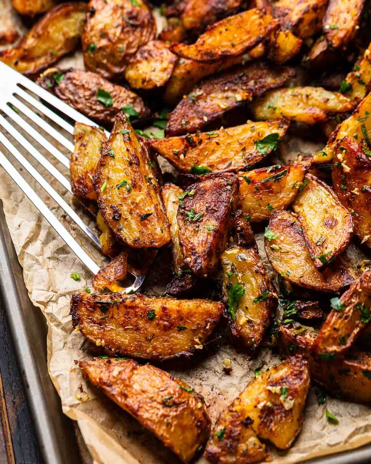 Baking sheet of roasted potatoes with spatula.