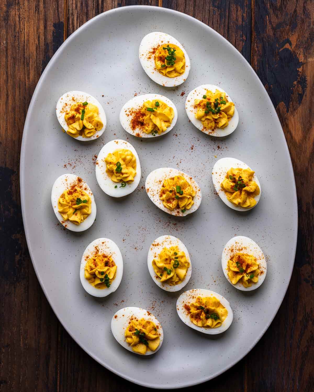 Large platter filled with classic deviled eggs on wood table.
