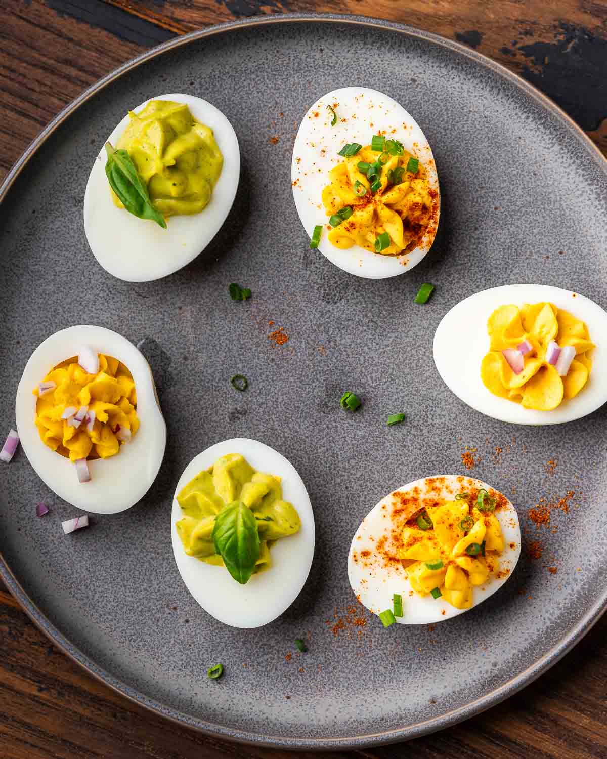 Deviled eggs with three types of filling on grey plate.