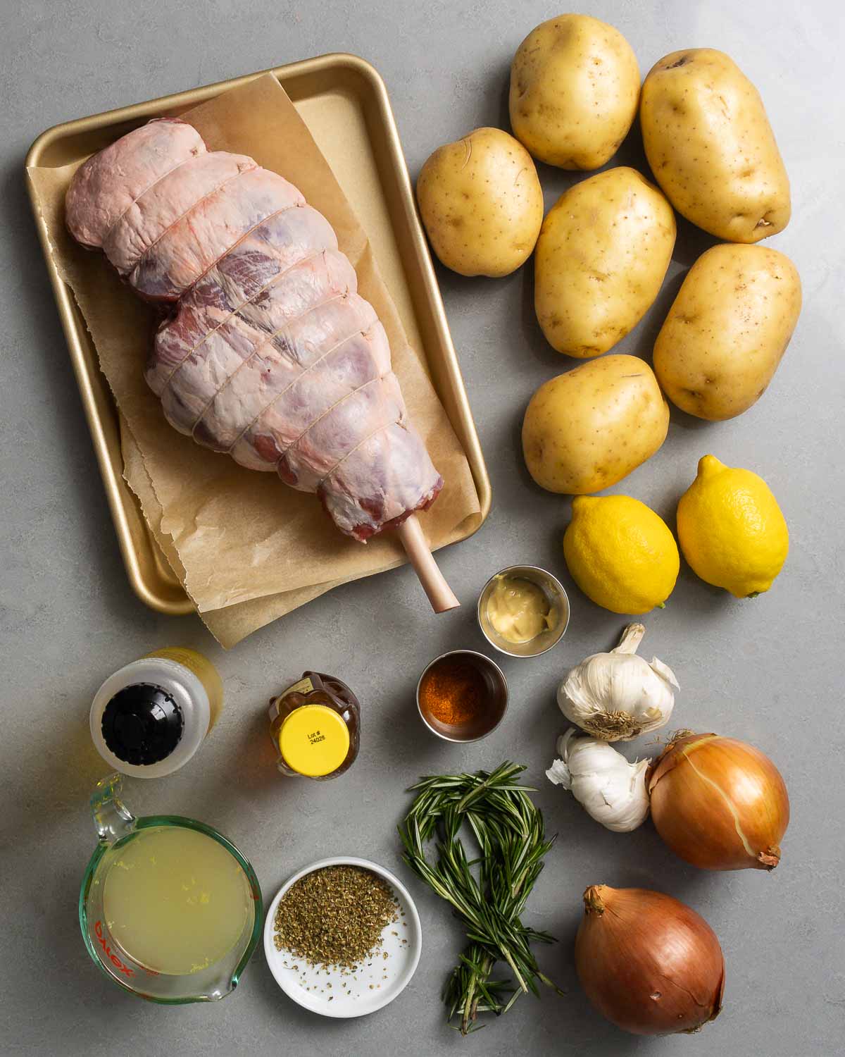 Ingredients shown: leg of lamb, potatoes, olive oil, honey, paprika, Dijon, lemons, garlic, chicken stock, oregano, and rosemary.