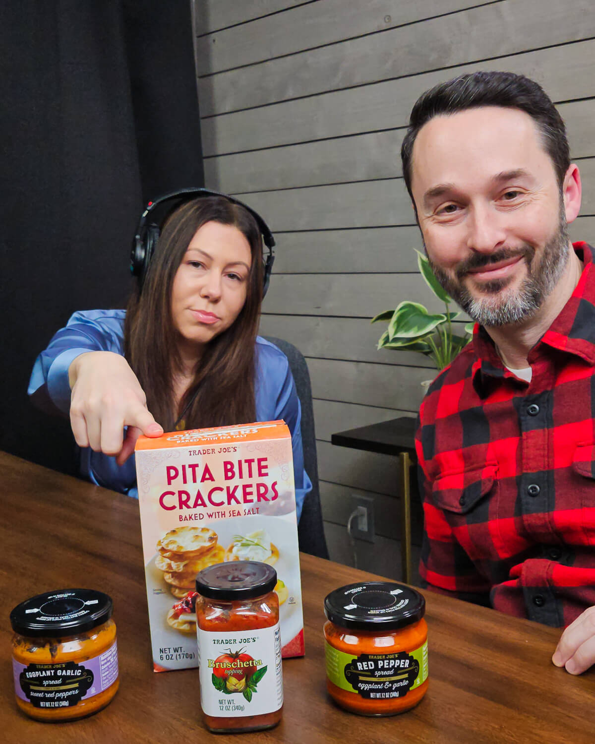 Jim and Tara in Podcast studio with box of Trader Joe's crackers, eggplant spread, red pepper spread, and bruschetta on table.