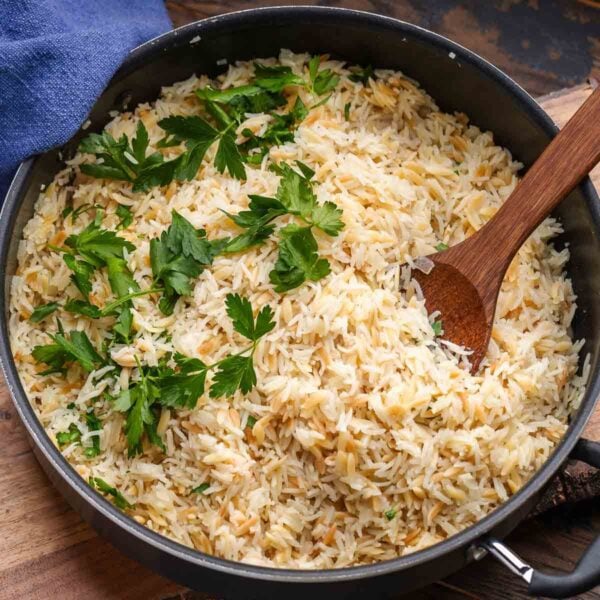 Rice pilaf in black pan with parsley garnish for featured image.