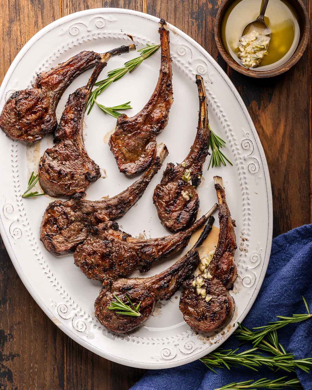 Platter of grilled lamb rib chops with bowl of lemon garlic sauce on the side.