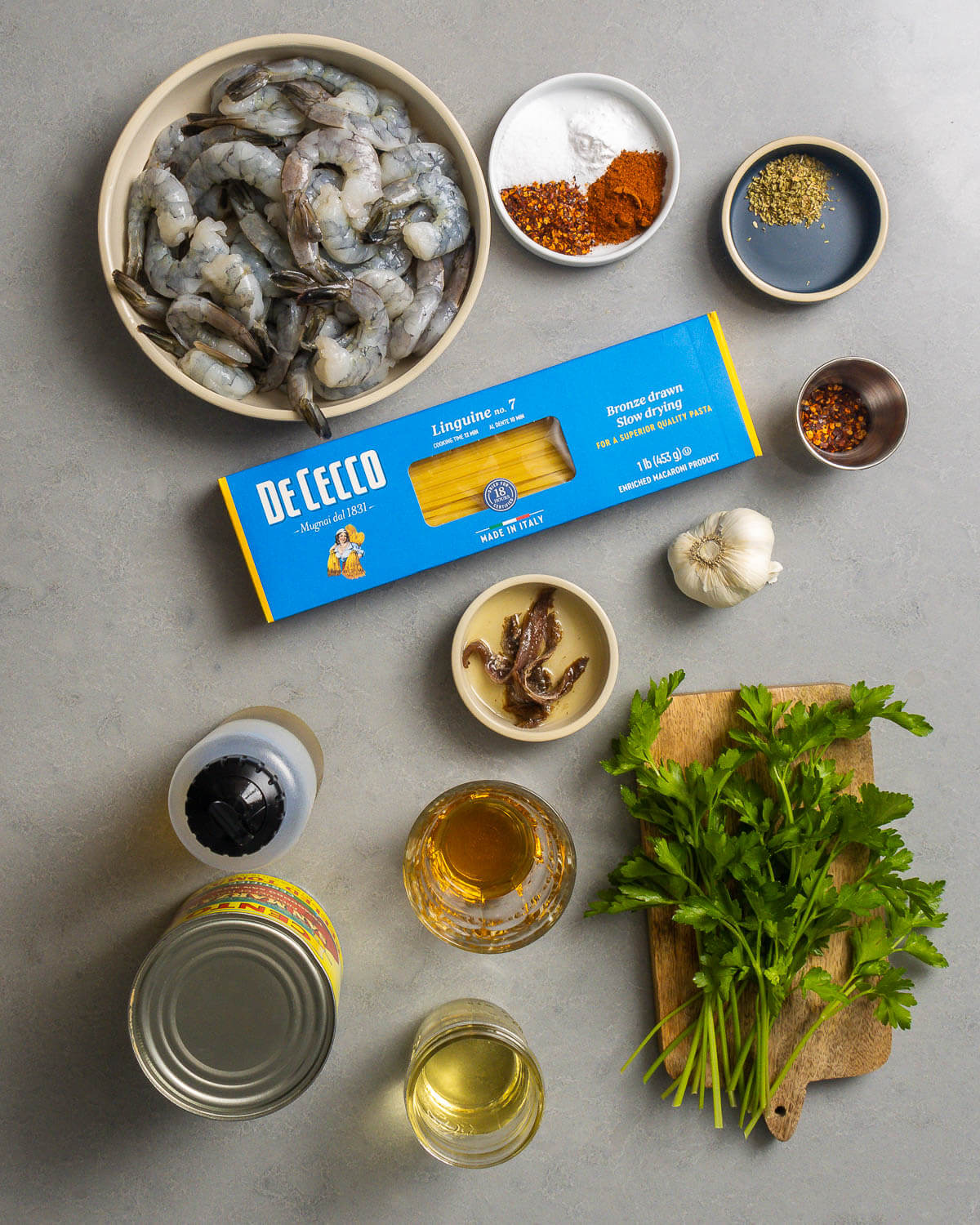 Ingredients shown: shrimp, spices, linguine, hot red pepper flakes, anchovies, garlic, olive oil, plum tomatoes, white wine, brandy, and parsley.