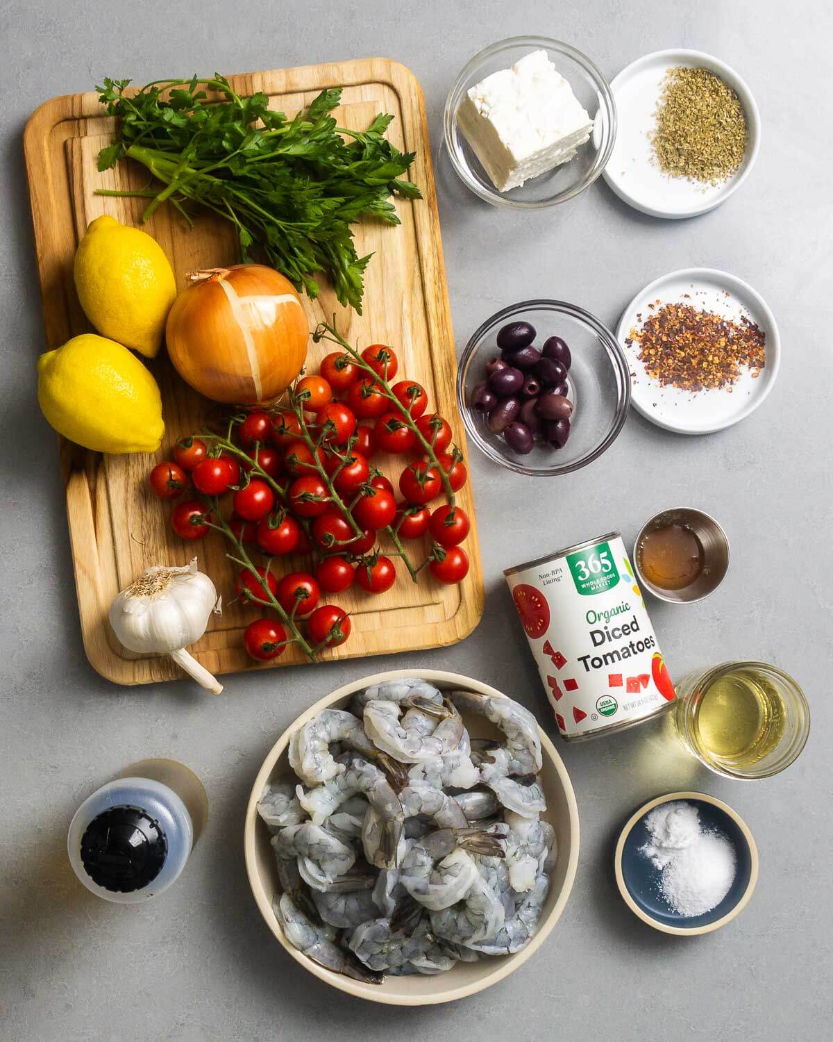 Ingredients shown: parsley, lemons, onion, cherry tomatoes, garlic, feta, oregano, kalamata olives, chili flakes, olive oil, shrimp, canned tomatoes, honey, wine, and baking soda.