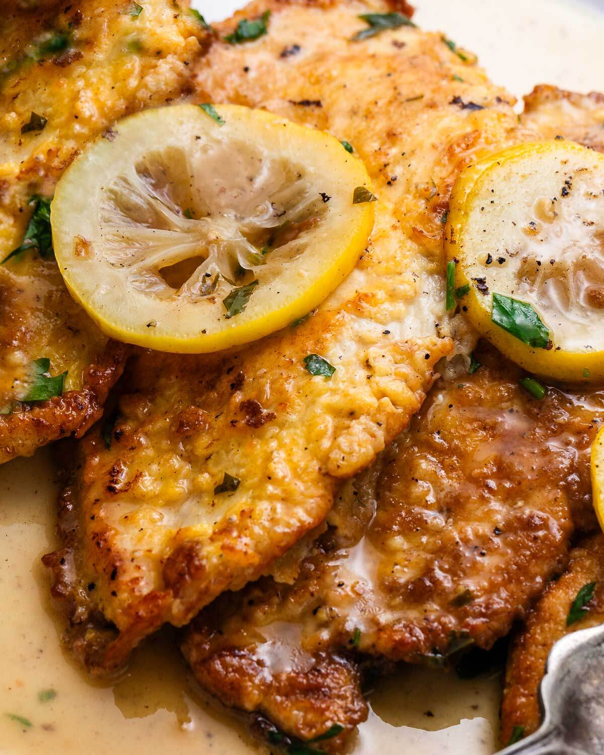 Chicken Francese in white platter with lemon slices.