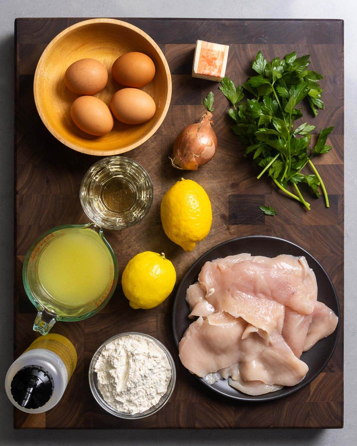 Ingredients shown: eggs, butter, shallot, parsley, white wine, chicken stock, lemons, olive oil, flour, and chicken cutlets.