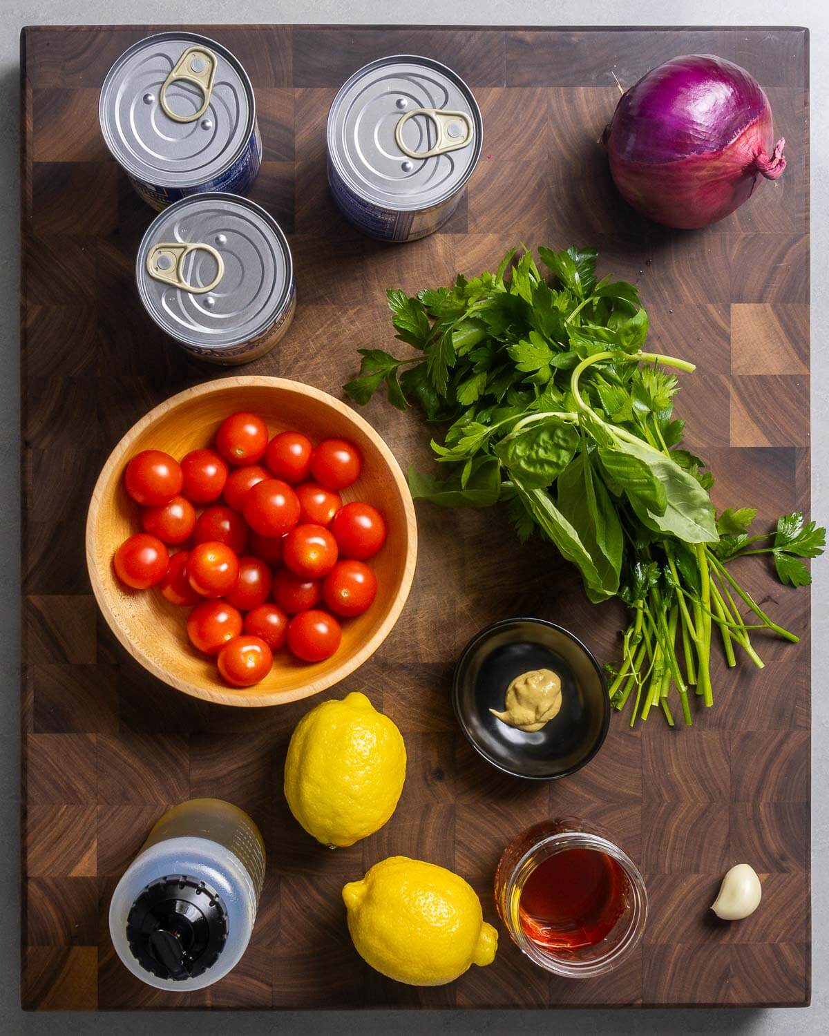 Ingredients shown: 3 cans of white beans, red onion, cherry tomatoes, parsley and basil, lemons, Dijon mustard, olive oil, red wine vinegar, and clove of garlic.