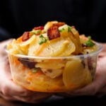 German potato salad in deli container held in hands.