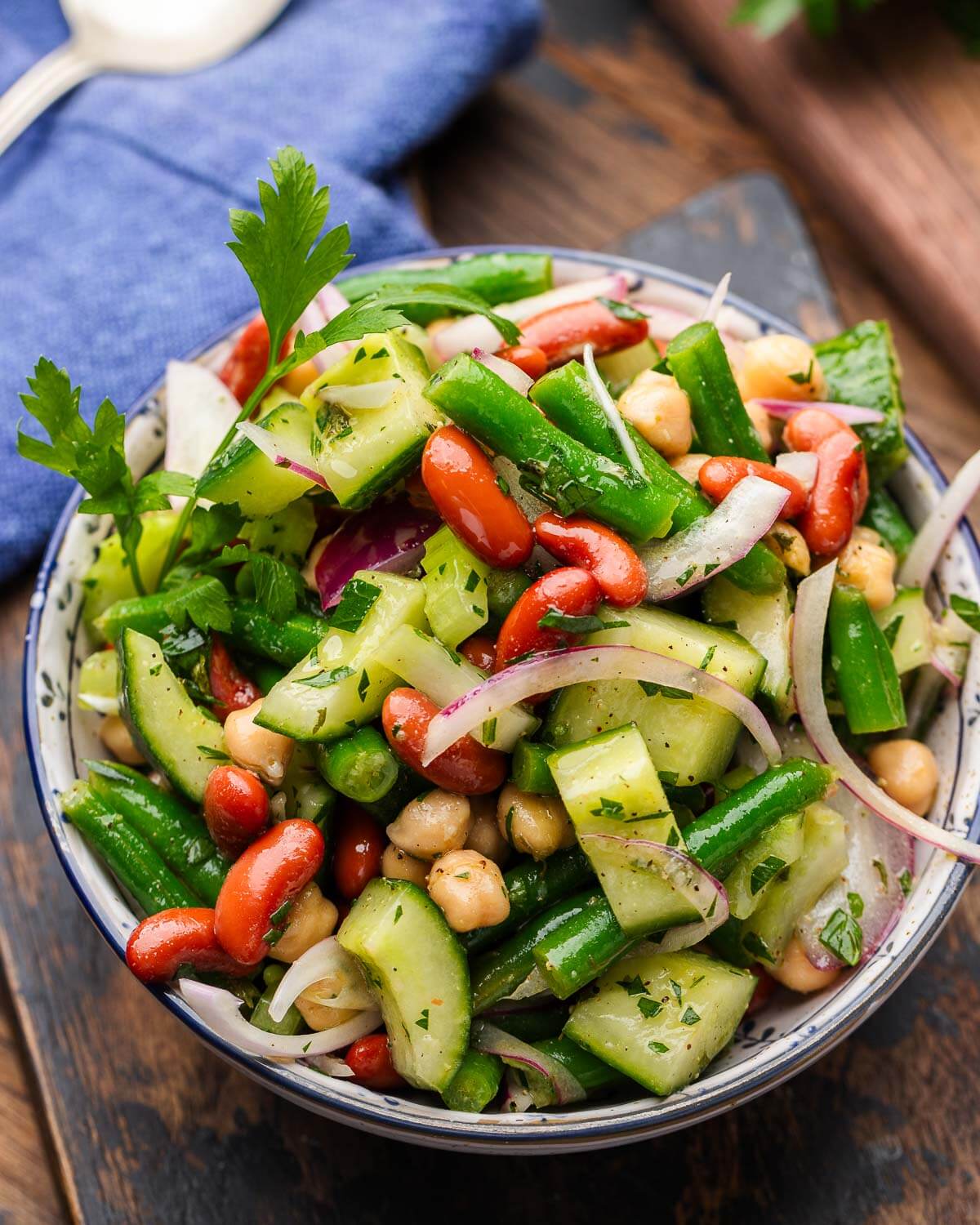 Mixed bean salad in white bowl garnished with parsley.