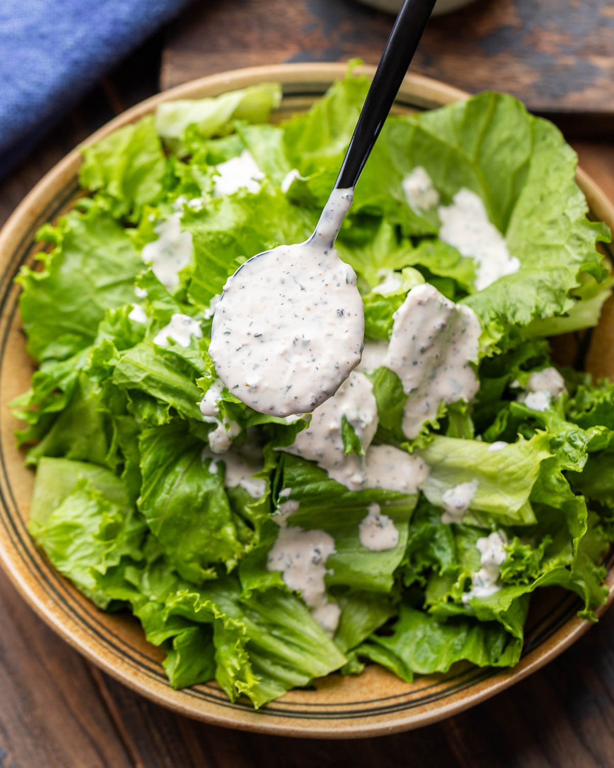 Creamy parmesan peppercorn dressing spooned over a bowl of salad.