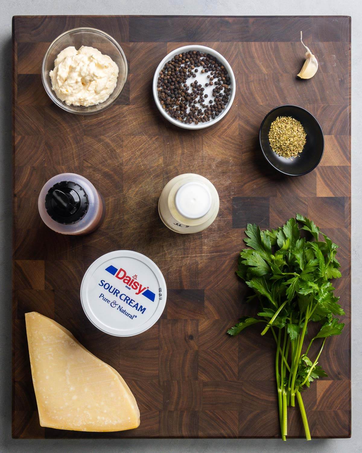Ingredients shown: mayonnaise, peppercorns, garlic, oregano, red wine vinegar, buttermilk, sour cream, Parmigiano Reggiano cheese, and parsley.