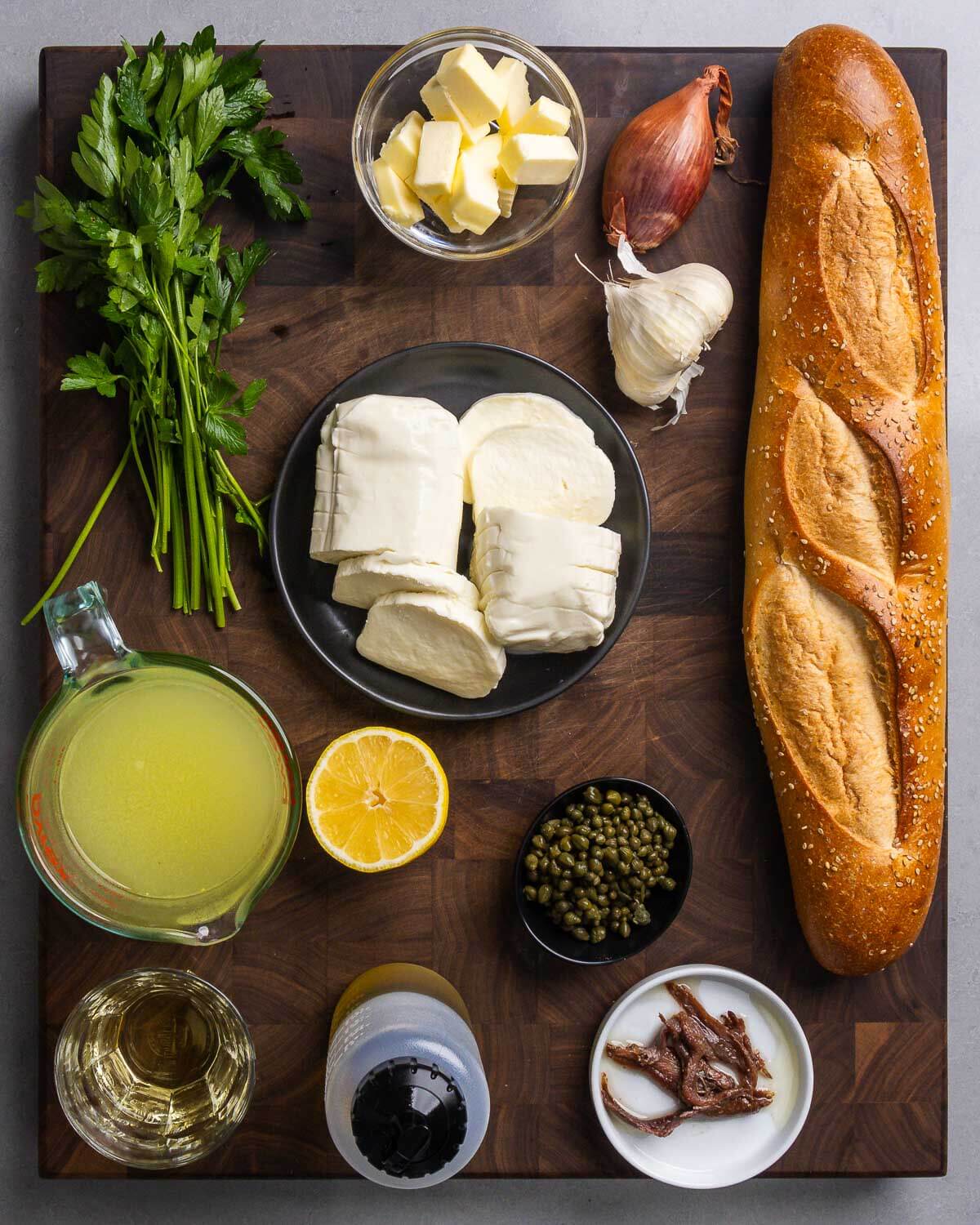 Ingredients shown: parsley, butter, shallot, garlic, Italian bread, fresh mozzarella, chicken stock, lemon, capers, white wine, olive oil, and anchovies.