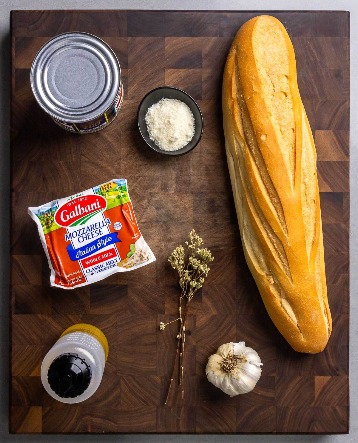 Ingredients shown: canned tomatoes, Pecorino Romano, French bread, mozzarella, olive oil, Sicilian oregano, and garlic.