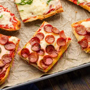 6 slices of French bread pizza on brown parchment paper lined baking sheet.