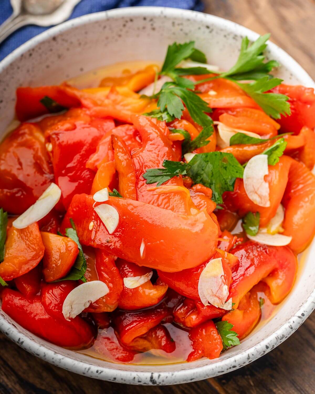 Large white bowl with Italian roasted red peppers with parsley garnish.