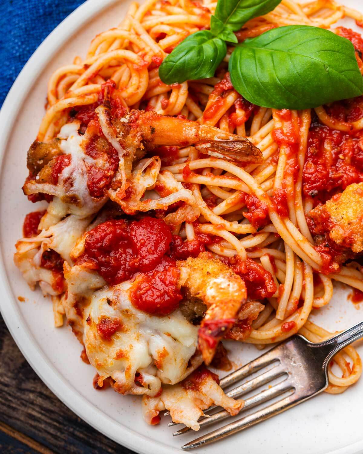 White plate with spaghetti and shrimp parmesan.