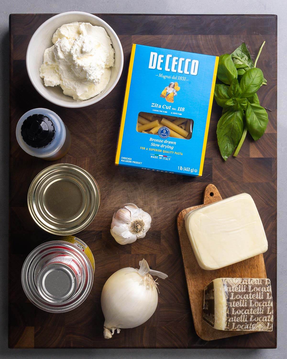 Ingredients shown: ricotta, ziti pasta, basil, olive oil, canned tomatoes and paste, garlic, onion, mozzarella, and Pecorino Romano.
