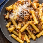 Grey plate with pasta alla Genovese topped with grated parmesan cheese.