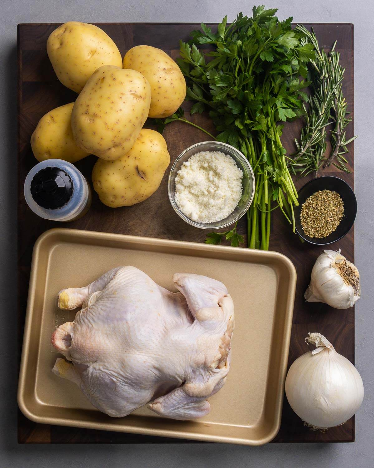Ingredients shown: potatoes, olive oil, parsley, rosemary, oregano, Romano cheese, garlic, onion, and a whole chicken.
