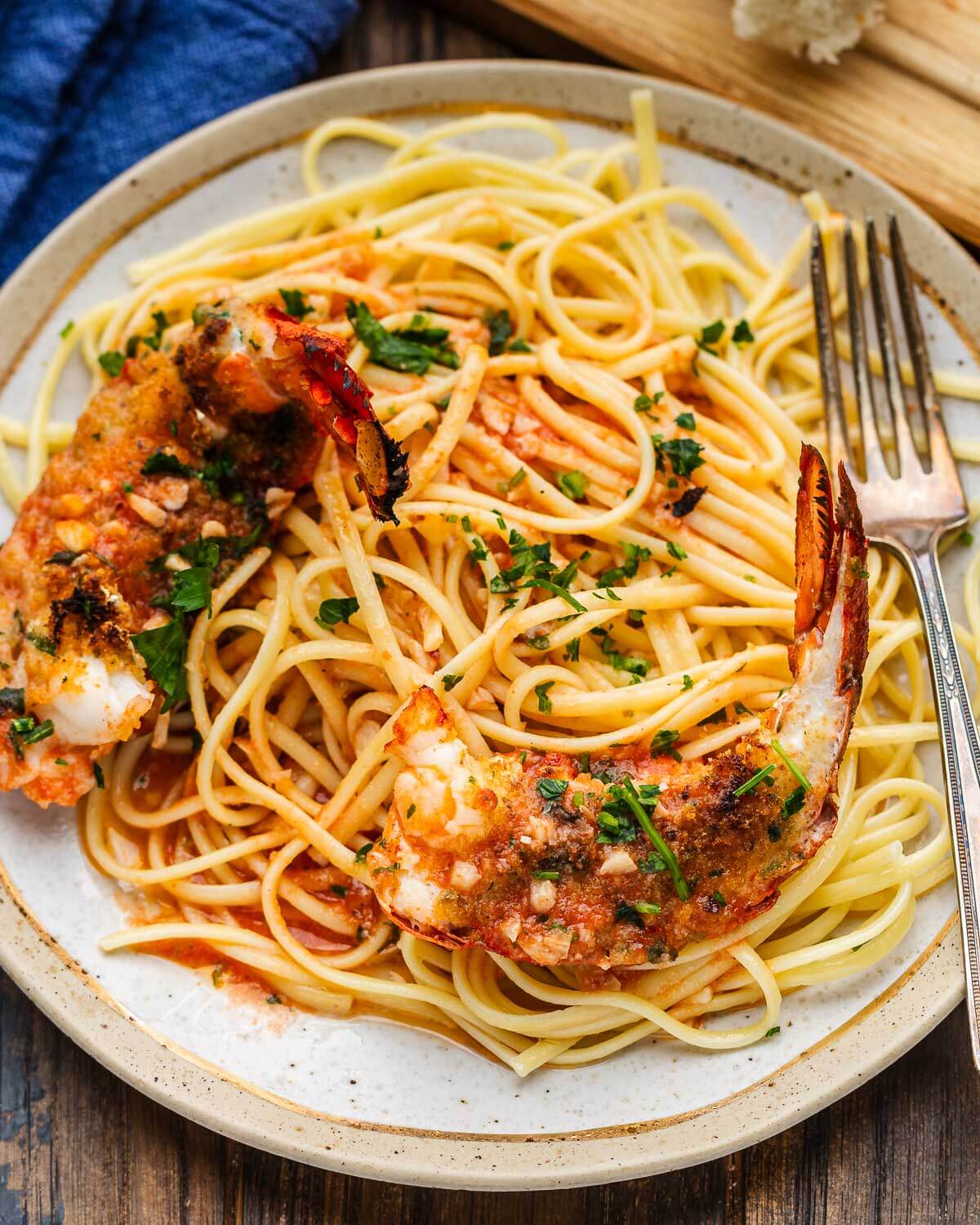 Two lobster tails with breadcrumbs on top of linguine.