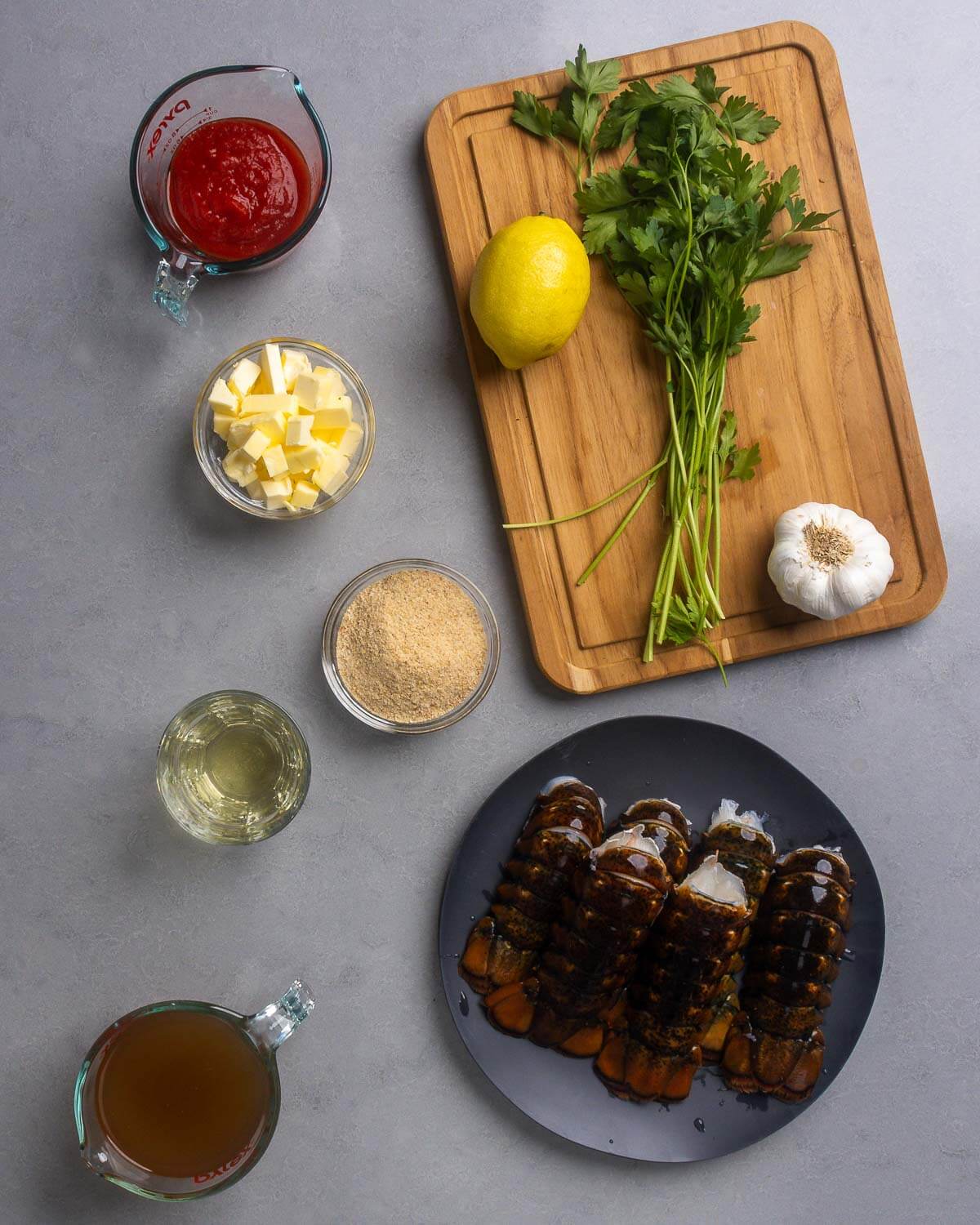 Ingredients shown: passata, cubed butter, lemon, parsley, garlic, breadcrumbs, white wine, chicken stock, and lobster tails.
