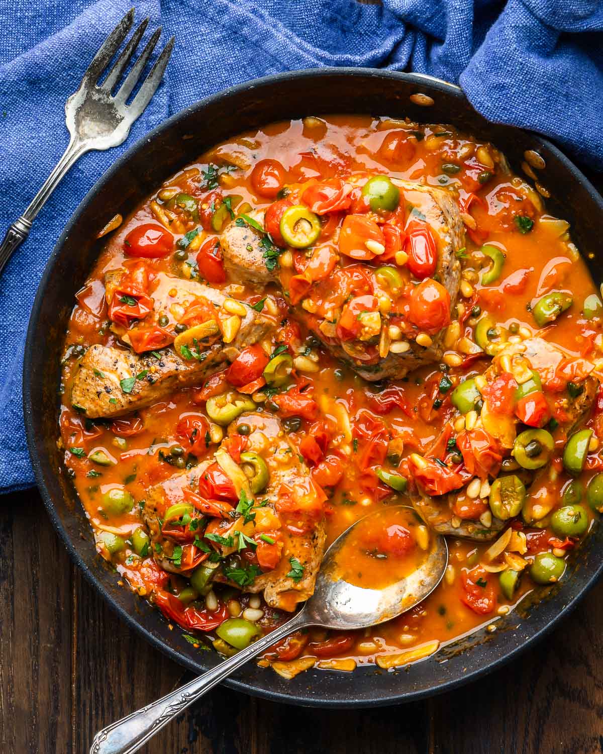 Large black pan with tuna steaks smothered in Sicilian style sauce.