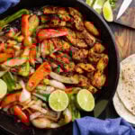 Large cast iron pan with chicken fajitas.