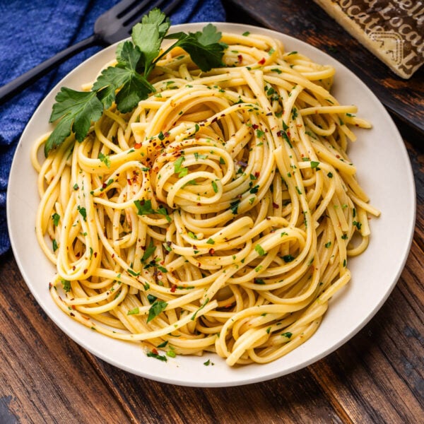 Linguine aglio e olio in white plate with parsley garnish.