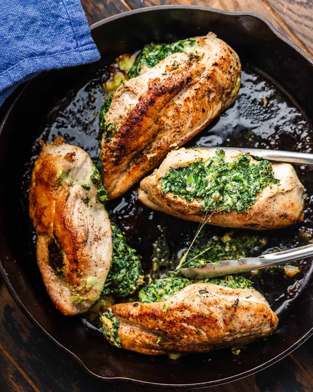 Four Spinach stuffed chicken breasts in cast iron pan.
