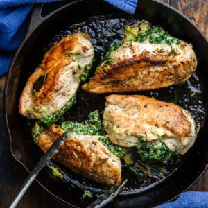 Four Spinach stuffed chicken breasts in cast iron pan.