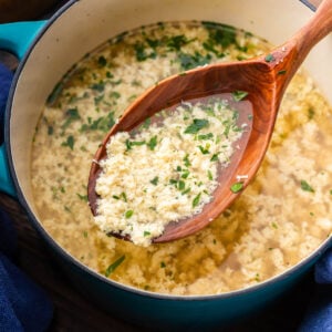 Ladle of stracciatella soup held over pot.