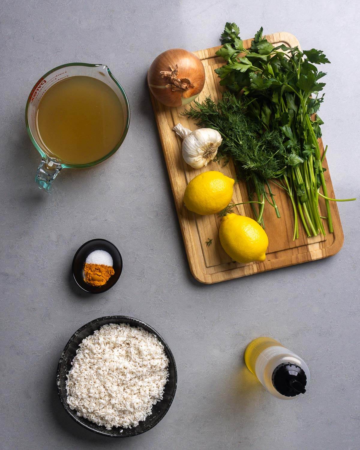 Ingredients shown: chicken stock, onion, garlic, dill, parsley, lemons, salt, turmeric, rice, and olive oil.