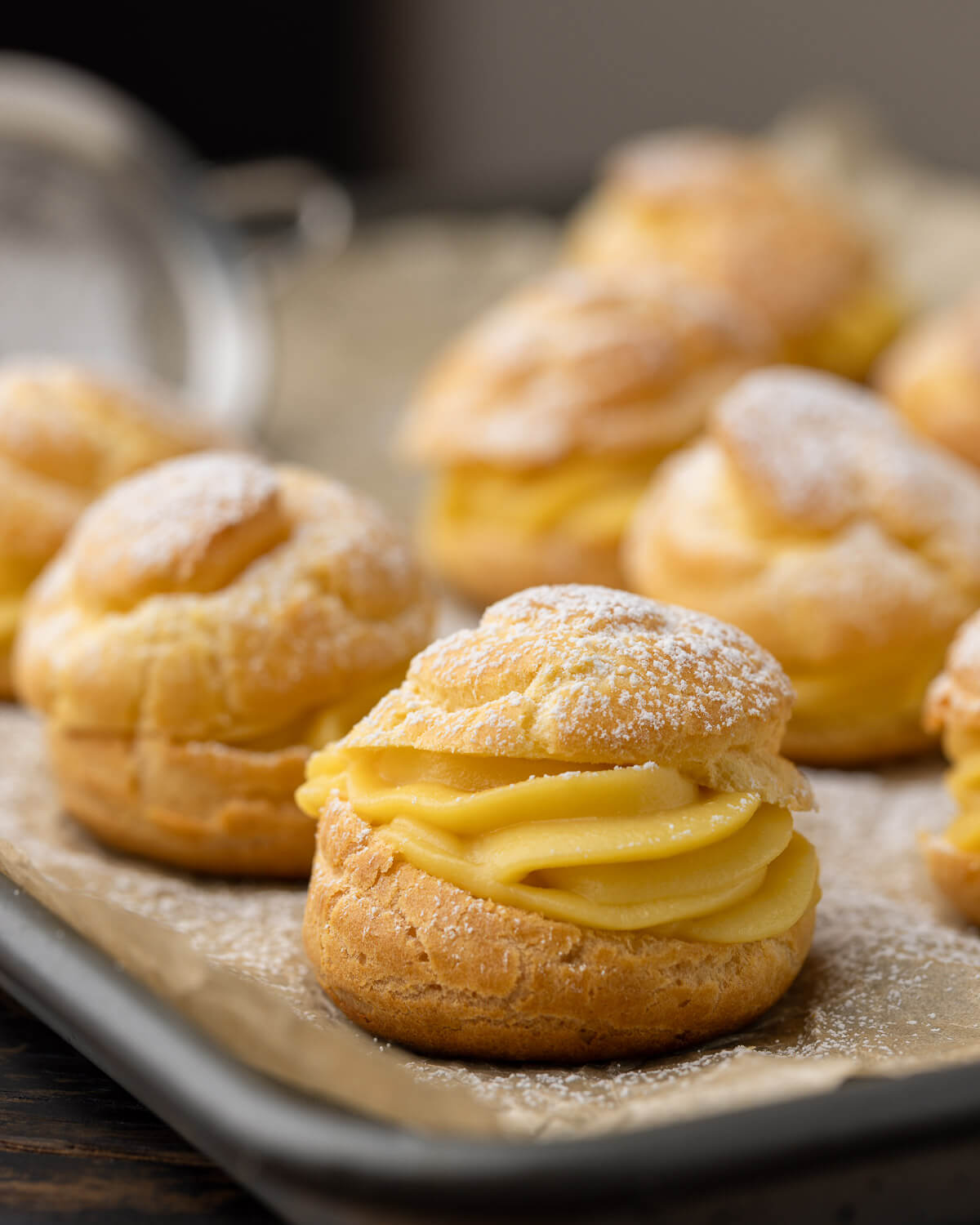 Cream Puffs with powdered sugar on baking sheet.