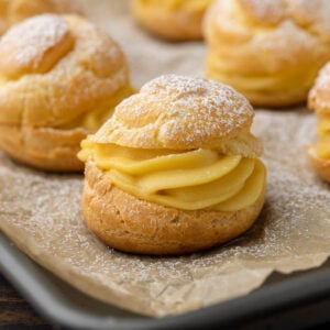 Cream Puffs with powdered sugar on baking sheet.