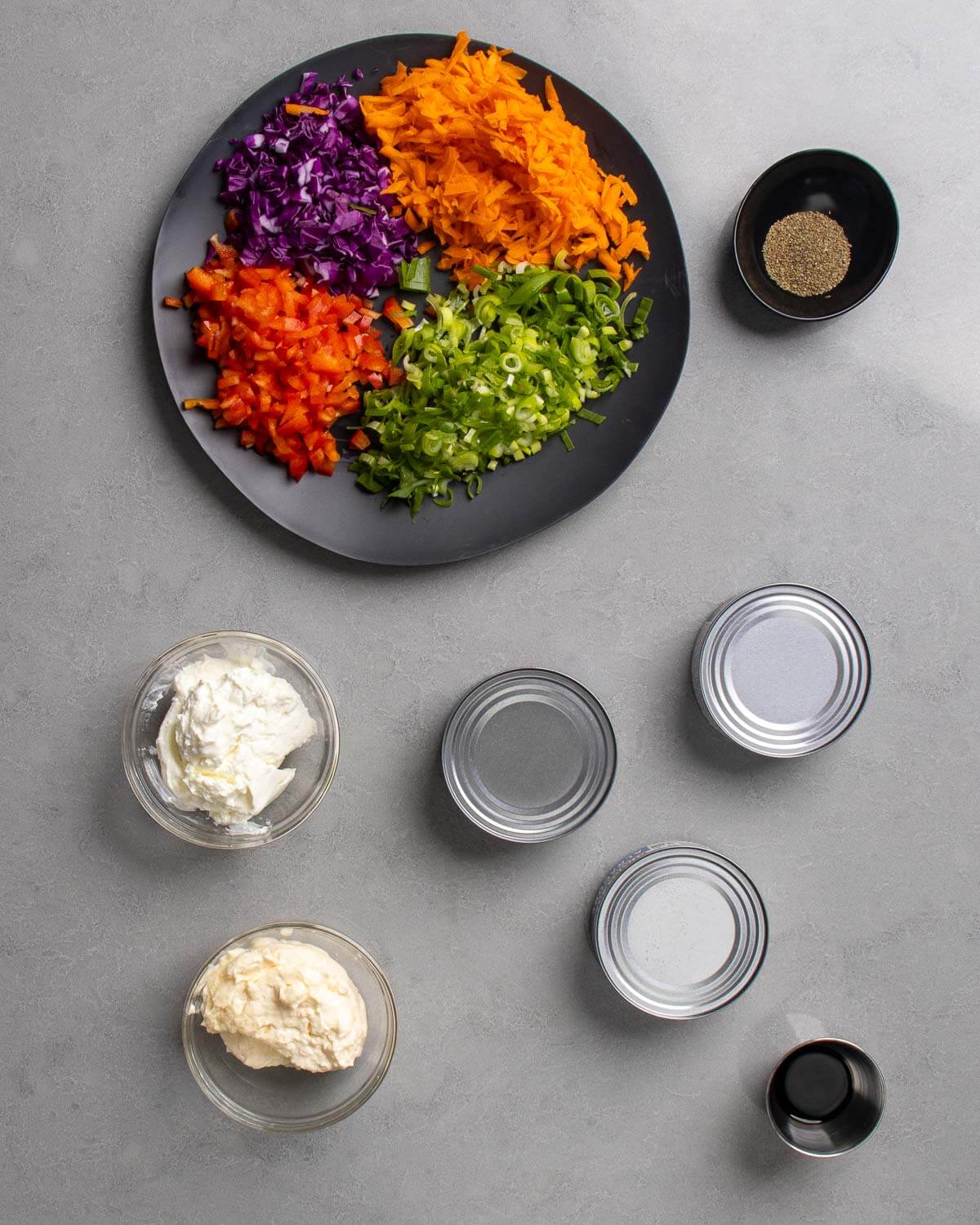 Ingredients shown: chopped carrots, cabbage, bell pepper, and greeen onions, celery seed, light mayonnaise, Greek yogurt, canned tuna, and soy sauce.