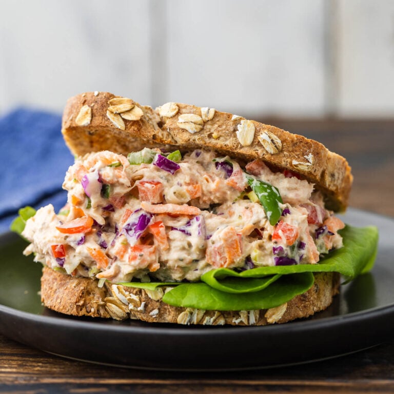 Healthy tuna salad on grain bread on black plate.