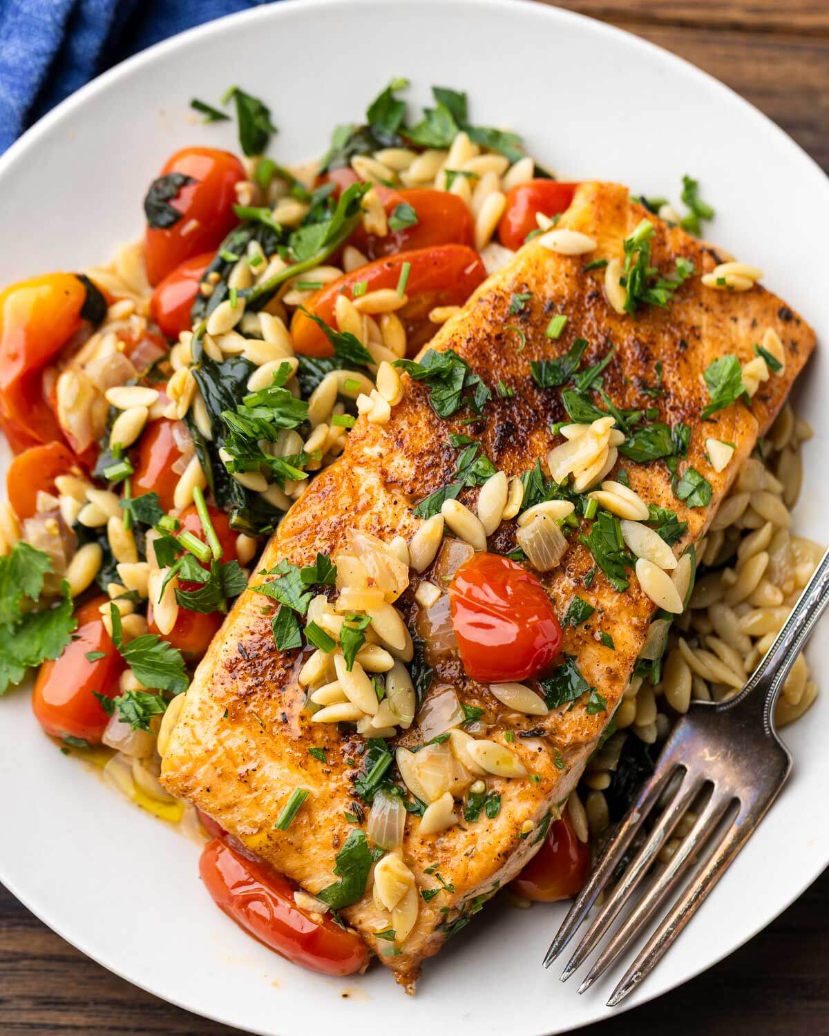 Salmon and orzo with spinach on white plate.