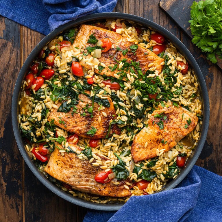One pan salmon with orzo on wooden table.