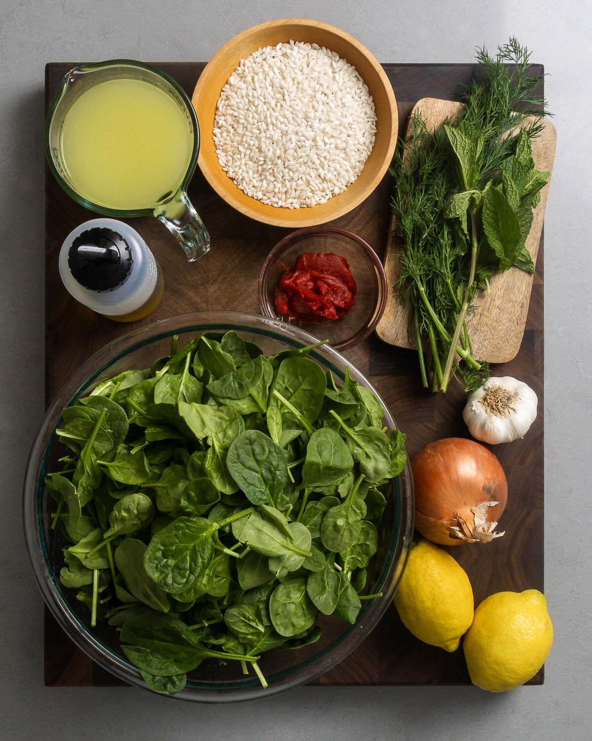 Ingredients shown: chicken stock, olive oil, rice, tomato paste, dill, mint, spinach, garlic, onion, and lemons.